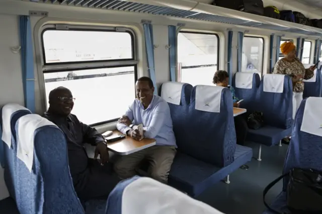 Kenyan passengers (L) pose for a photograph while on board an economy class car in one of the new passenger trains using the new Mombasa to Nairobi Standard Gauge Railway (SGR