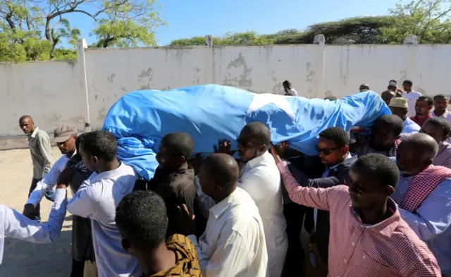 Mourners carry the body of Mr Abas