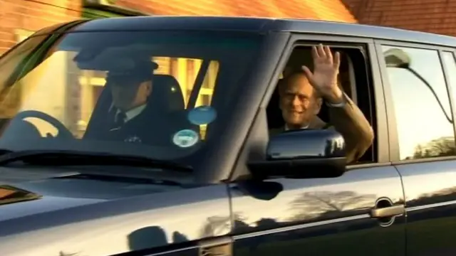 The Duke,waving from the front seat of a car