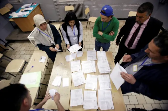 Election workers count ballots at the end of voting for the parliamentary election in Algiers