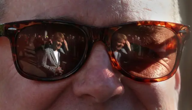 First Minister Nicola Sturgeon reflected in a pair of sunglasses at a photo call with the SNP"s new council group in Glasgow"s George Square