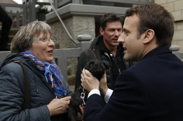 French presidential election candidate for the "En Marche!" (Onwards!) political movement, Emmanuel Macron (R) greets a woman and her dog - 7 May 2017