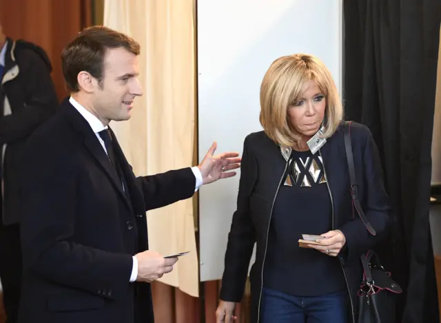 Emmanuel Macron (L) and his wife Brigitte Trogneux (R) prepare to cast their ballots at a polling station in Le Touquet, northern France, 7 May