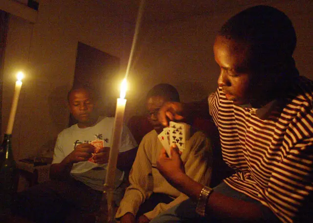 Men play cards by candlelight