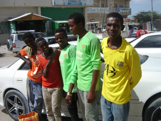 Team of young men stand next to a car in Hargeisa