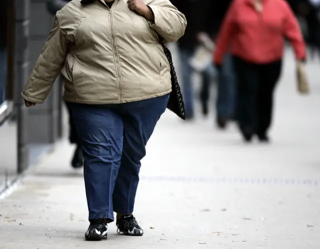 An overweight woman walking down a street