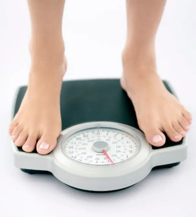 A young woman standing on a pair of scales