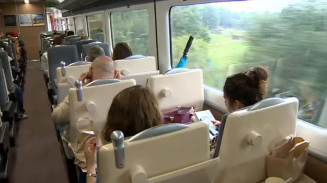 Interior of rail carriage, showing passengers in seats