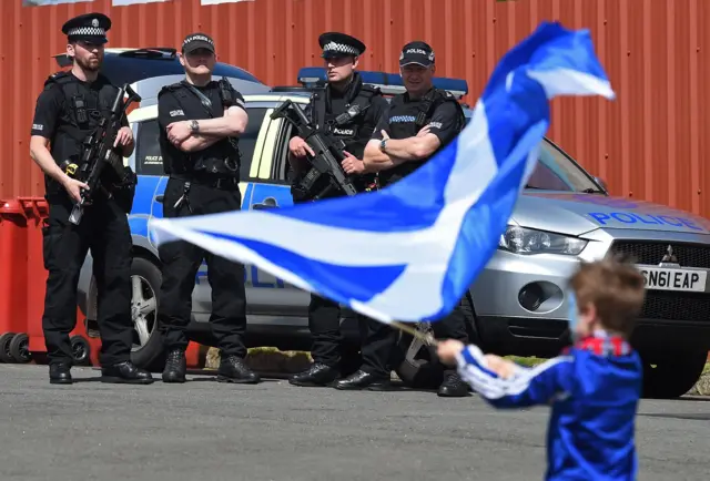 A young Scotland supporter with armed police in the background