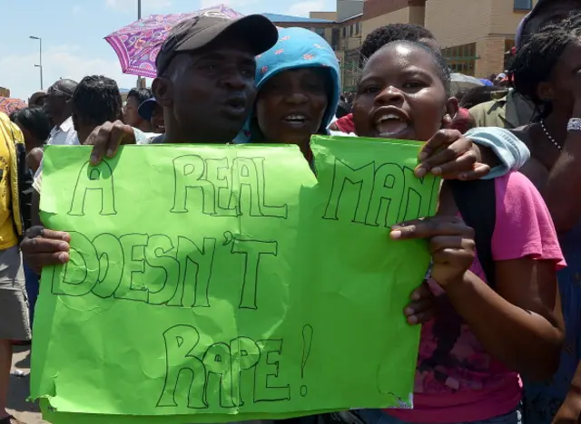 Protesters hold on October 18, 2013 a placard reading 'A Real Man Doesn't Rape !' during a demonstrating in Diepsloot, north of Johannesburg, after five people were arrested for the rape and murder of two toddlers in a shantytown