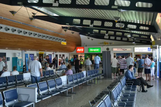 People waiting for passengers coming out of arrivals in Guernsey Airport terminal