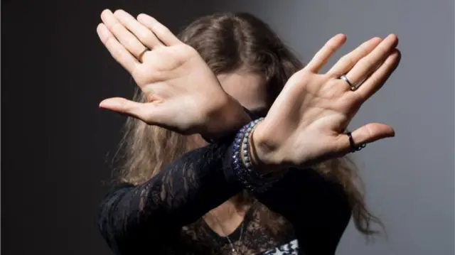 Woman holding here hands out to shield her