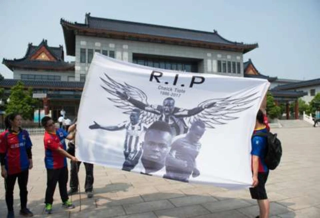 Fans hold a Cheick Tiote flag