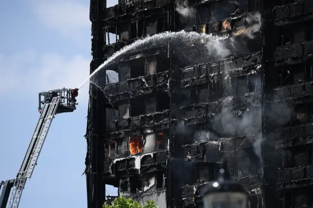 A hose spraying water on a blackened building