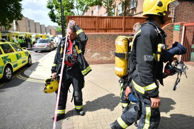 Firefighters work at the scene where a fire ripped through Grenfell Tower, a residential block in west London on June 14, 2017.