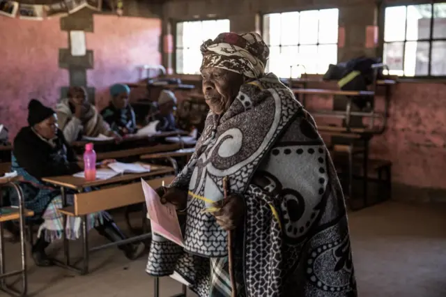 A Mosotho woman walks to mark her ballot