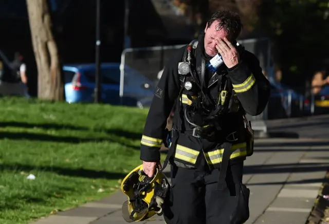 A firemen appears to wipe away tears and sweat after battling a huge fire at the Grenfell Tower