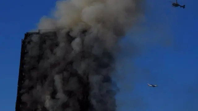 A helicopter and an aeroplane are seen as flames and smoke billow