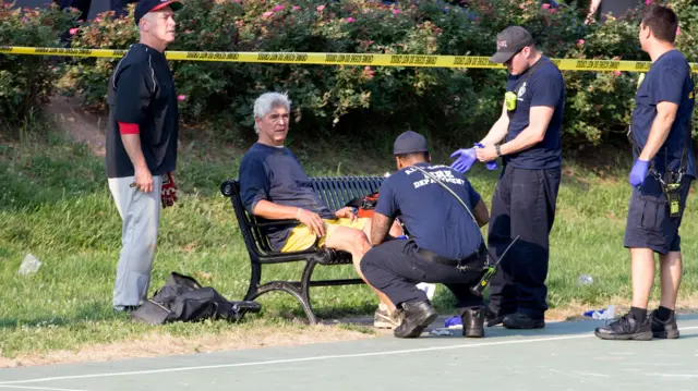 A man receives medical attention from first responders at the scene following the shooting in Alexandria