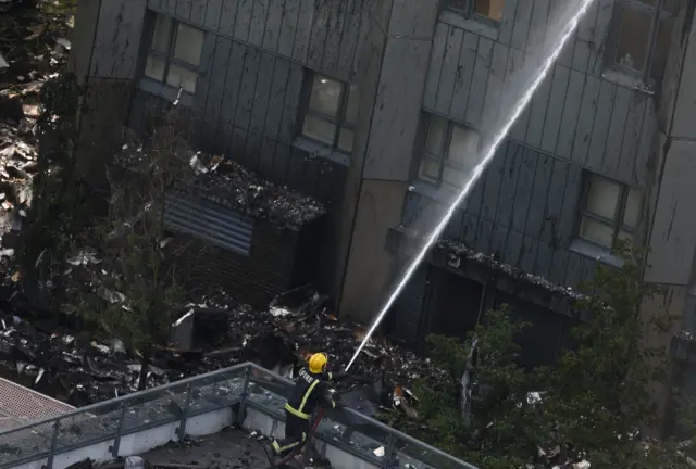 A firefighter directs a jet of water toward Grenfell Tower which was decimated in a fire