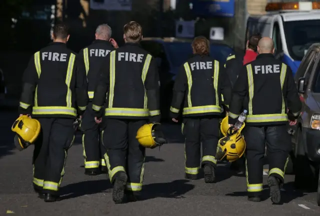 Members of the Fire Brigade walk near Grenfell Tower, a residential block of flats in west London on June 14, 2017, as firefighters continue to control a fire that started in flats in the early hours of the morning.