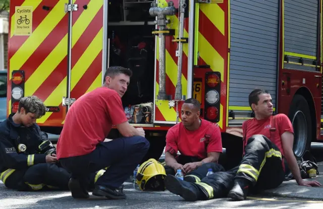 Firefighters rest by their truck