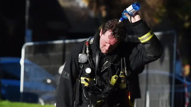 A firefighter pours water over his head