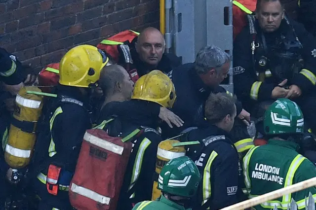 A man is rescued by firefighters at the scene of the Grenfell Tower blaze