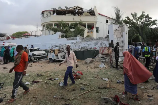 People stands outside the scene of an attack on a hotel and an adjacent restaurant in Mogadishu, Somalia June 15, 2017