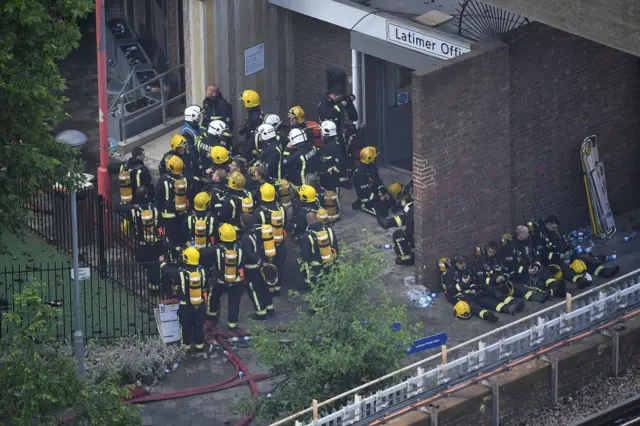 Firefighters gather near to the scene of the Grenfell Tower blaze