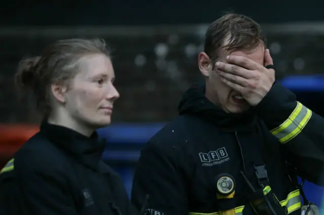 A firefighter covers his face at the scene of the Grenfell Tower