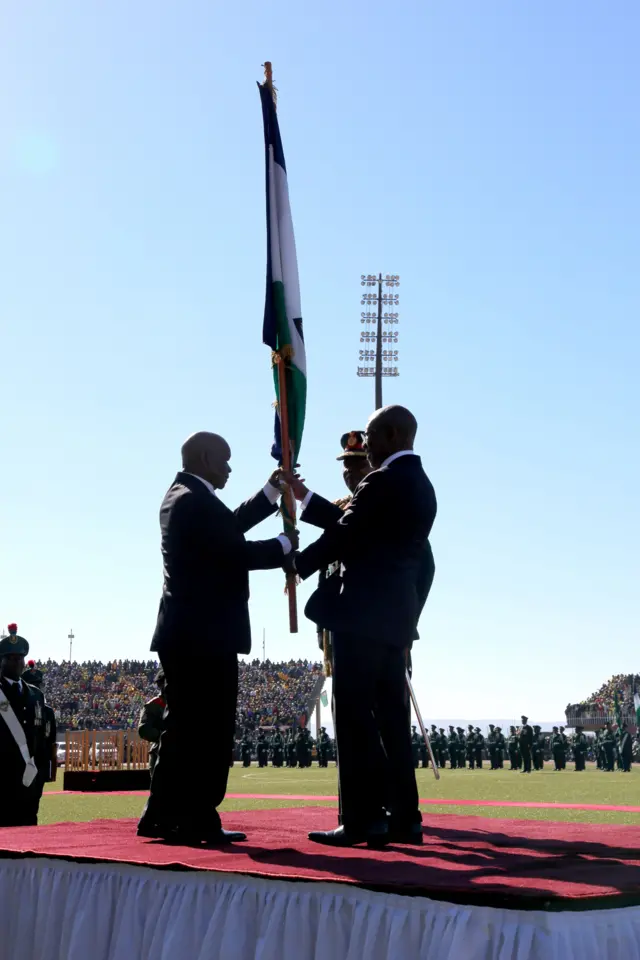 Newly appointed Lesotho prime Minister Thomas Thabane (L), leader of the All Basotho Convention (ABC) political party, receives the nation flag of Lesotho from former Prime Minister Pakalitha Mosisili (R) during his inauguration on June 16, 2017 in Maseru.