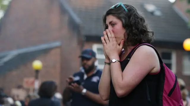 A woman looks at tributes close to Grenfell Tower in west London Friday June 16, 2017