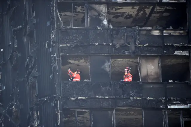 Members of the emergency services work inside the charred remains of the Grenfell apartment tower block in North Kensington