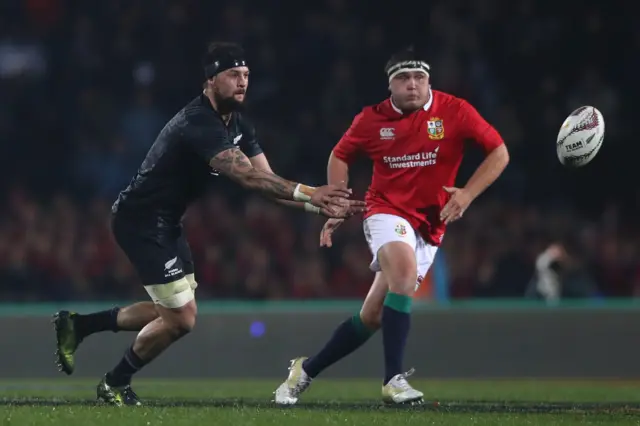 Elliot Dixon of the Maori All Blacks passes the ball as Jamie George of the Lions closes