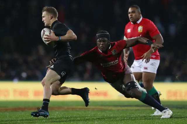 Damian McKenzie of the Maori All Blacks is tackled by Maro Itoje