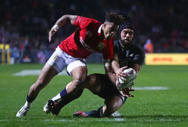 Charlie Ngatai of the Maori All Blacks cleans up the loose ball under pressure from Anthony Watson of the Lions