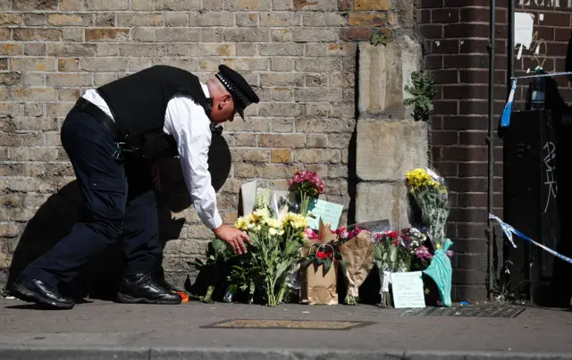 A police officer lays flowers at the scene