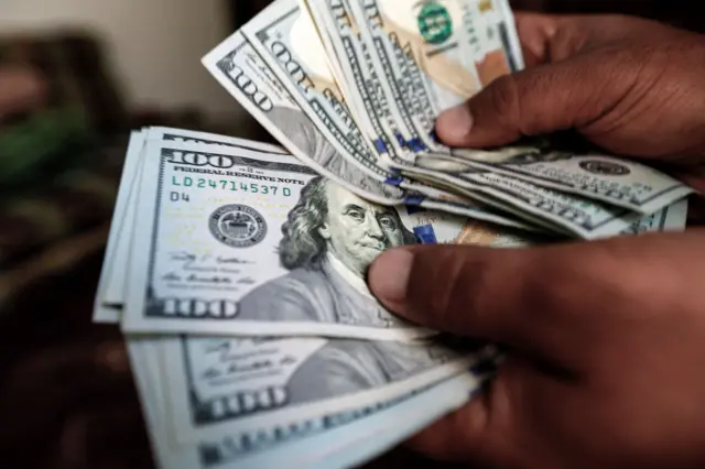 A Yemeni employee counts one hundred US dollar notes at a currency exchange office in the capital Sanaa on February 12, 2017.