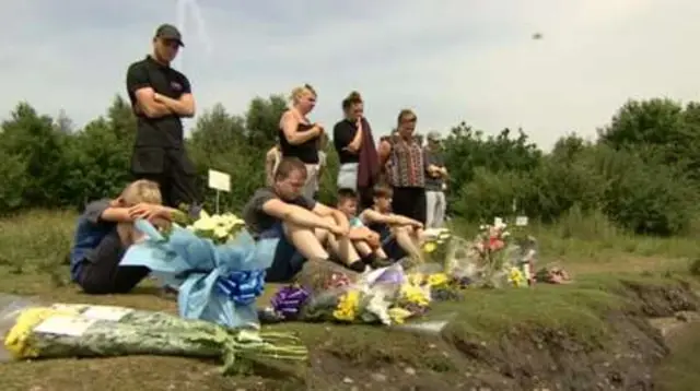 People laying tributes by lake's edge