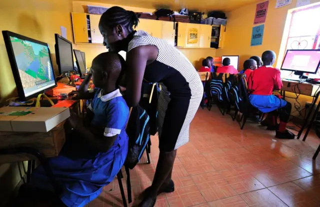 Teacher Emily Monje (R) shows pupils of Kibera School for Girls how to use computers at Nairobi on May 19, 2016.