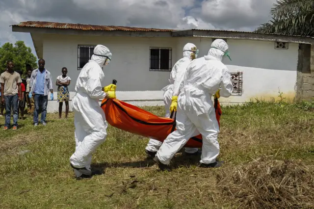 A Liberian Red Cross burial team retrieves the body of a suspected victim of Ebola in Banjor, on the outskirts of Monrovia, Liberia 24 October 2014