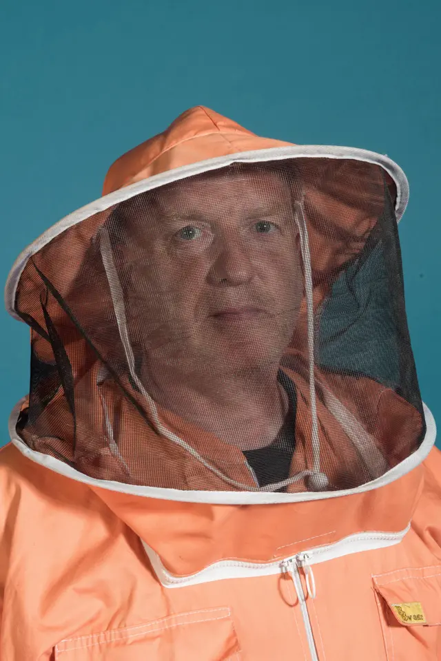 A man in a beekeeper hat and veil