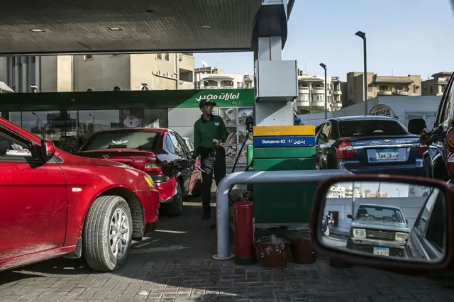 An Egyptian worker fills a customers tank as cars queue at a petrol station in the capital Cairo on November 4, 2016.