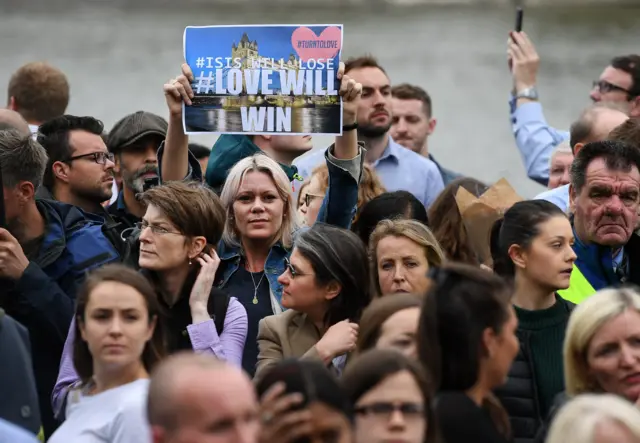 A woman holds up a sign saying "Love will win"