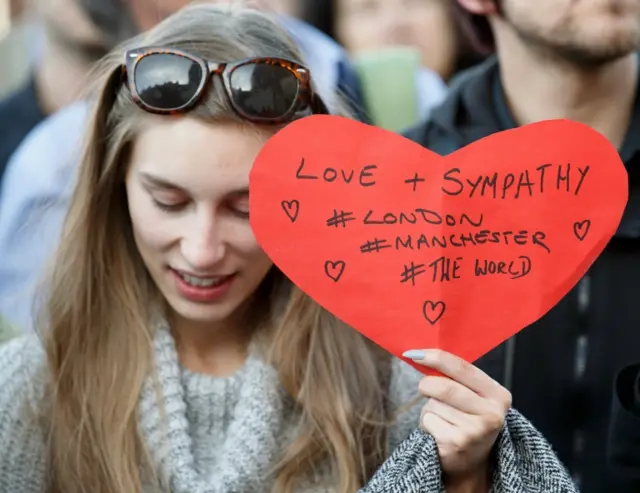 A supporter holds a sign of condolence for the victims of the London attack