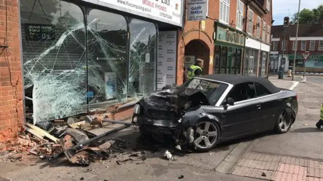 Car and shop window badly damaged after collision.