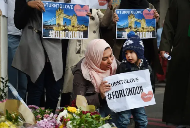 Members of London"s muslim community hold signs of condolence and support near the site of the attack