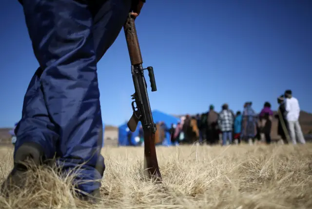 A police officer watches as voters wait in the queue to cast their vote during national elections at Semonkong, Lesotho June 3, 2017.