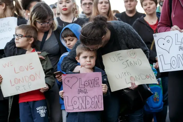 Supporters hold signs of condolence for the victims of the London attacks,